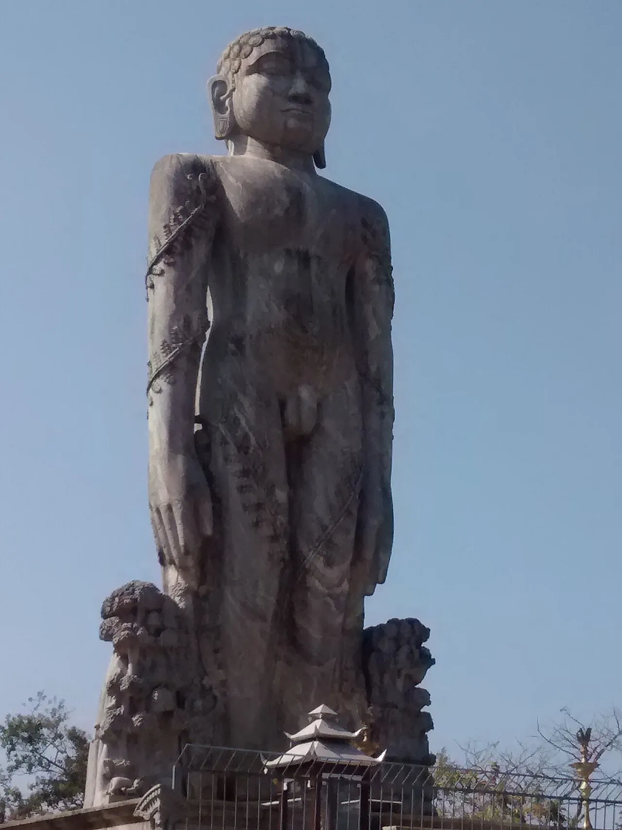 The tall stone statue of Bahubali at Dharmasthala, standing against a clear sky