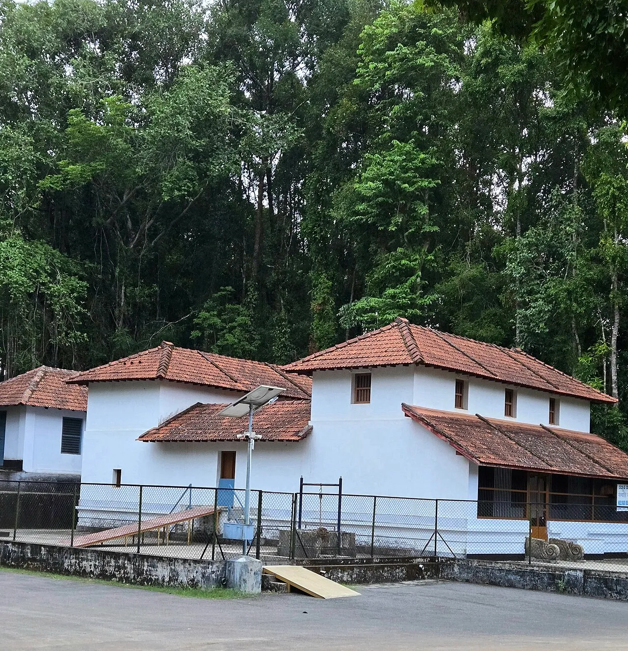 Nelyadi Beedu, the Pergade family's old house at Dharmasthala: white walls and red-tiled roofs against tall forest