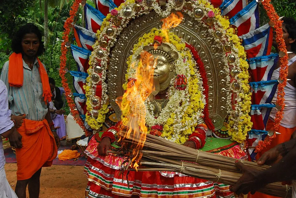 A daiva performer with torches during a bhuta kola