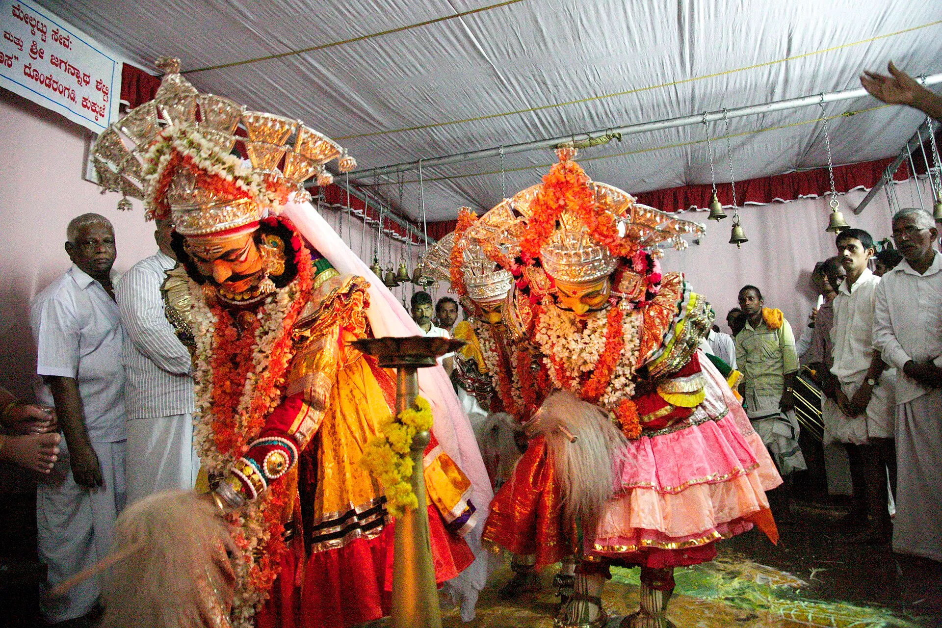 Two performers in tall crowns, flower garlands and painted faces embody the twins at a Baidarkala nema