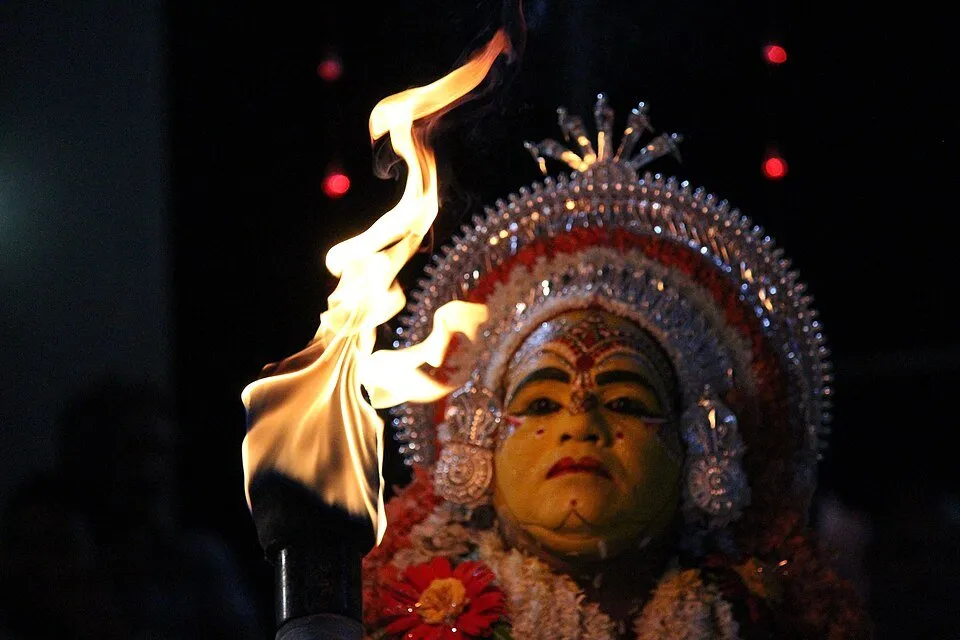 The painted face of Jarandaya at a kola, with a flame beside it