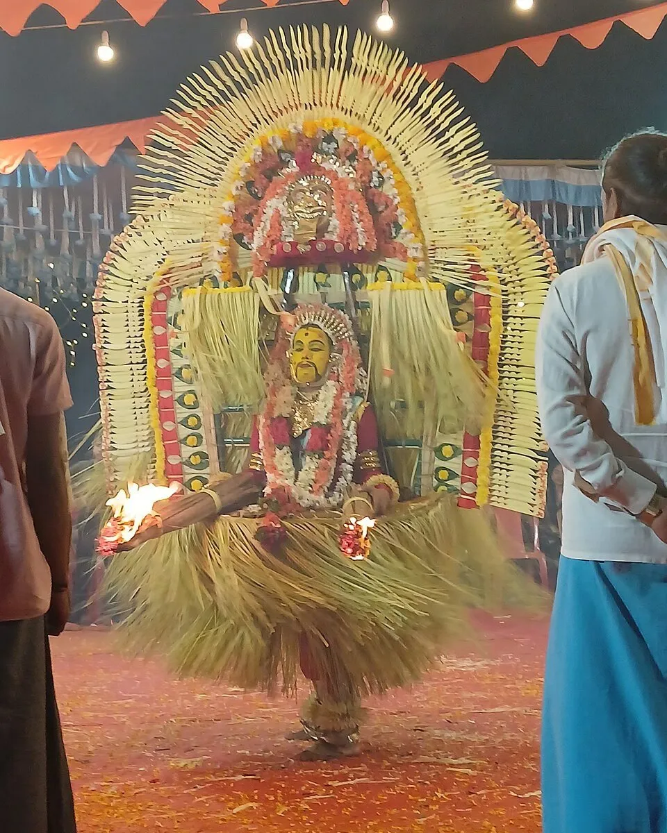 Kordabbu at a kola, in a tall halo headdress with sparks flying