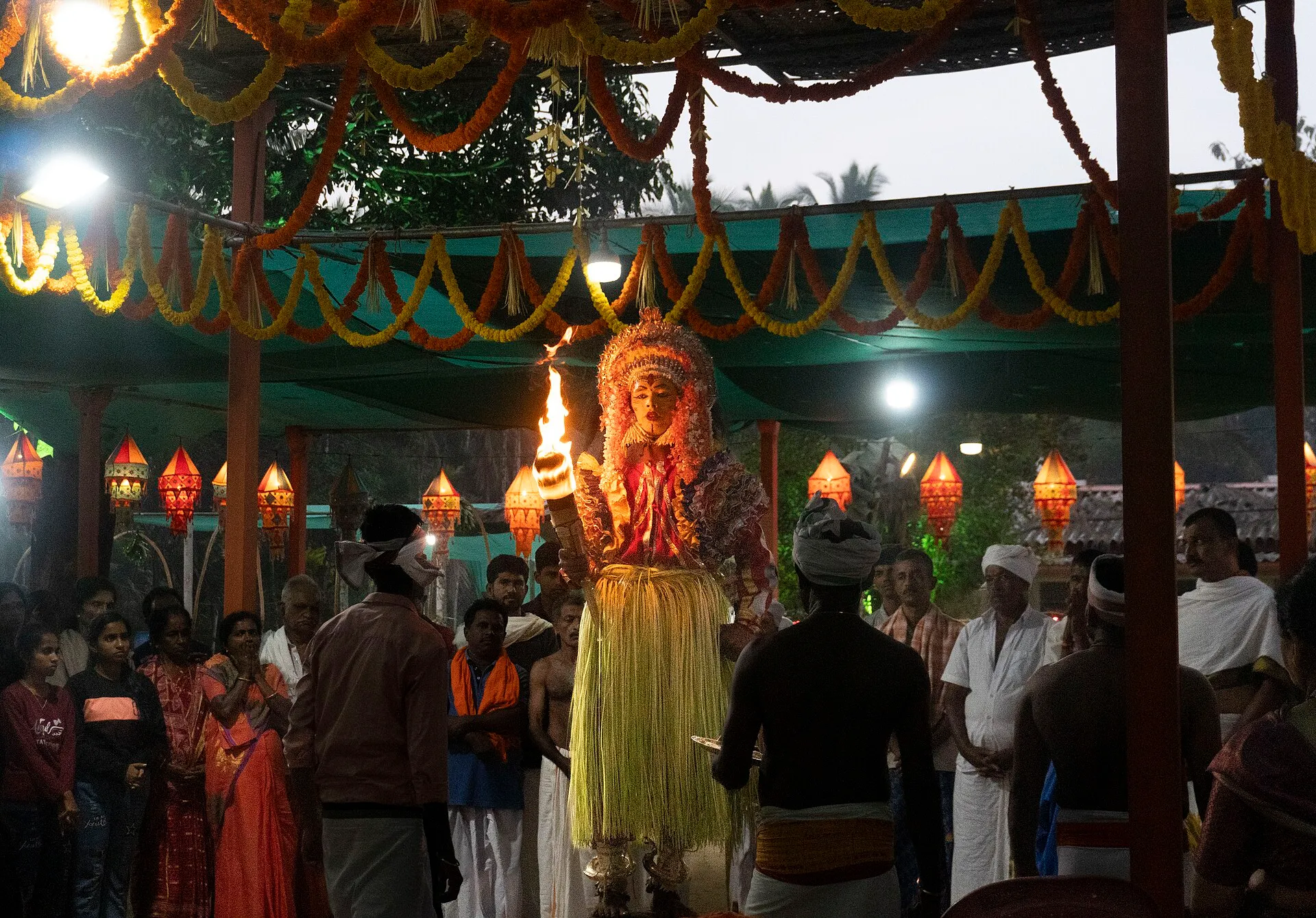 Panjurli, the boar daiva, among the crowd at a kola as night falls