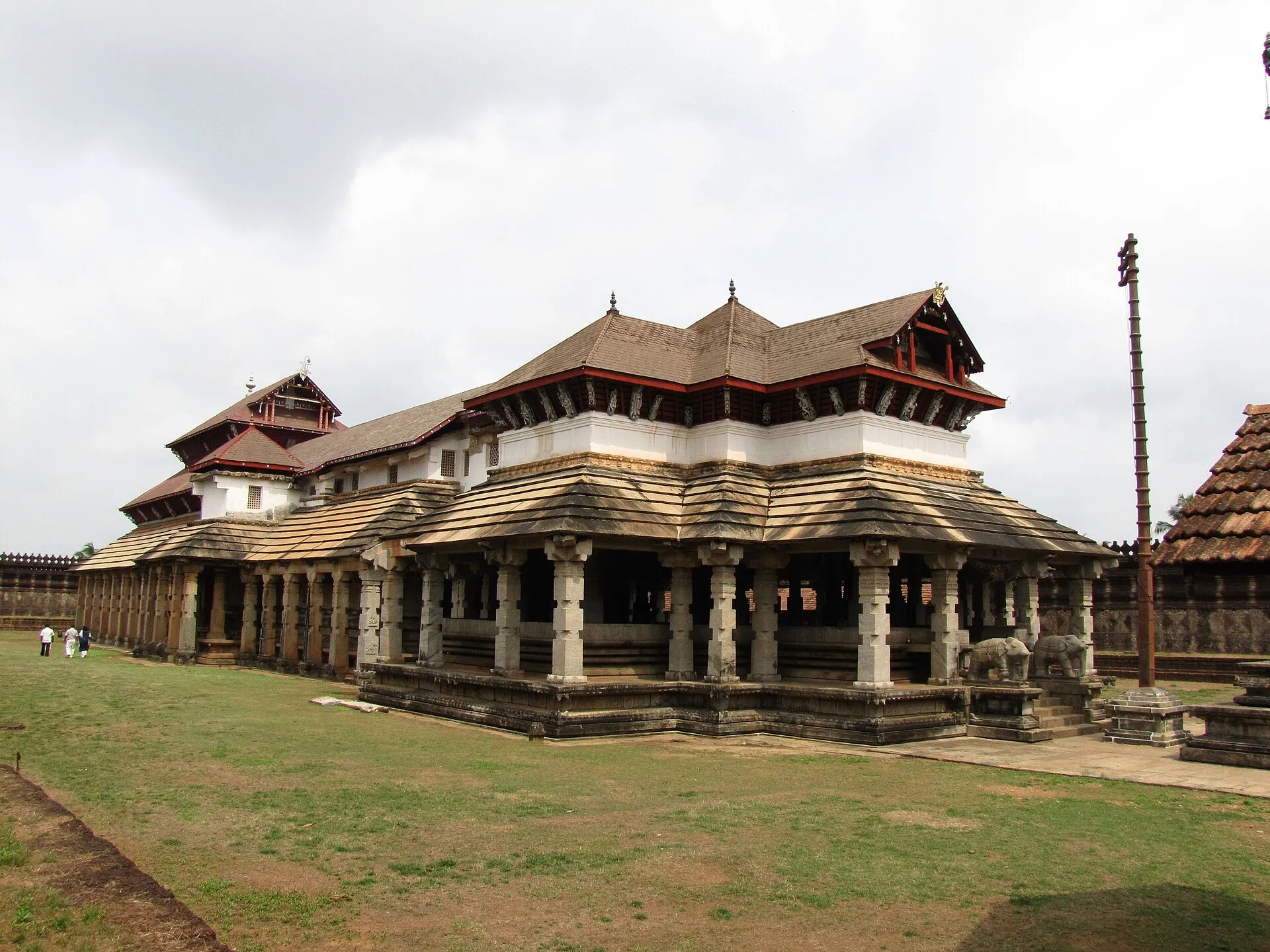 The Thousand Pillar Basadi at Moodabidri, a long stone temple with pillared verandas under tiers of sloping copper roofs, on a lawn