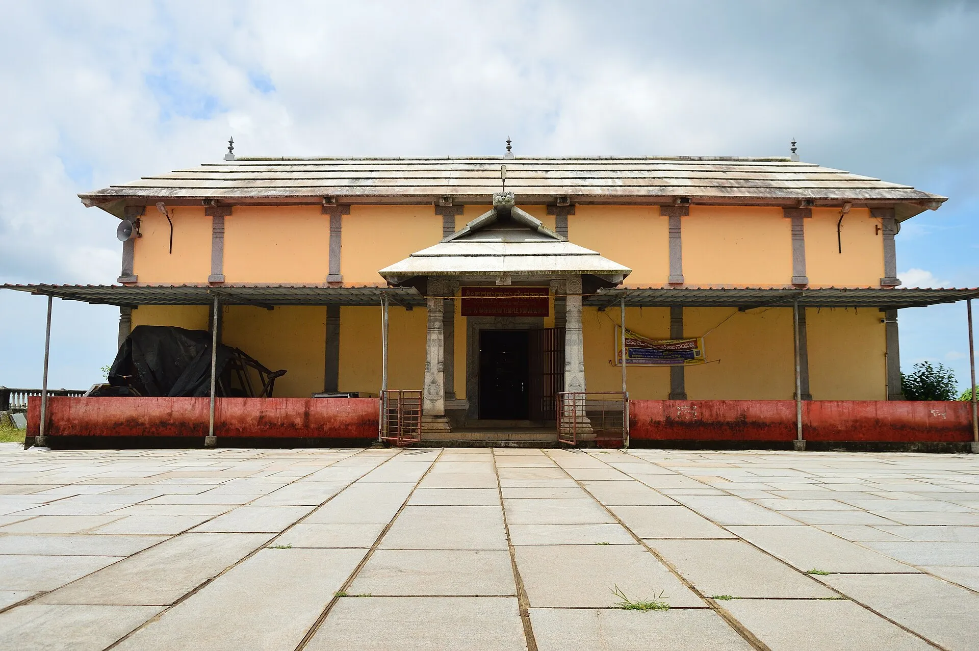 A long, low tiled-roof temple at the end of a wide stone-paved courtyard