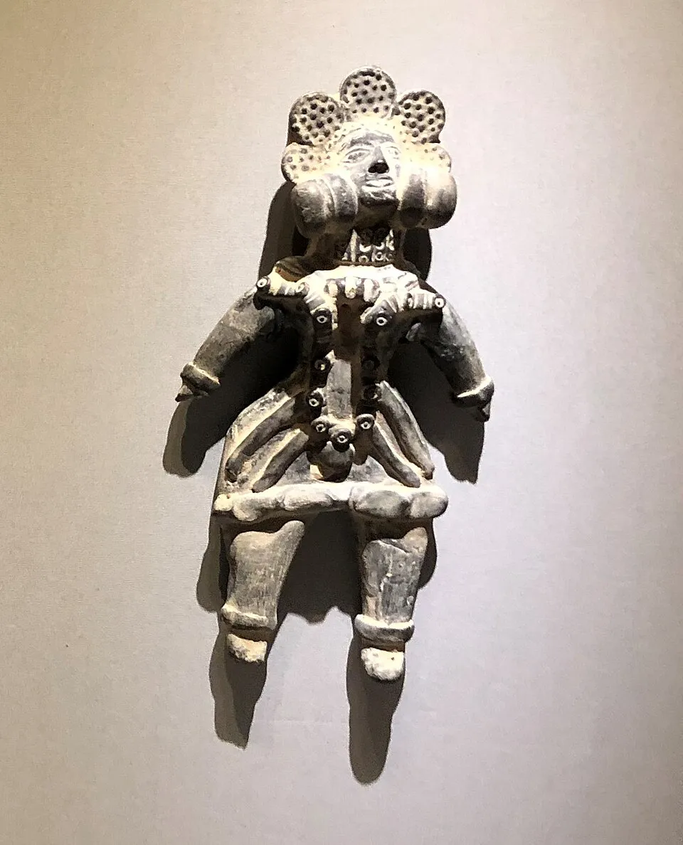 A terracotta mother-goddess figurine with a flower-like headdress and heavy necklaces