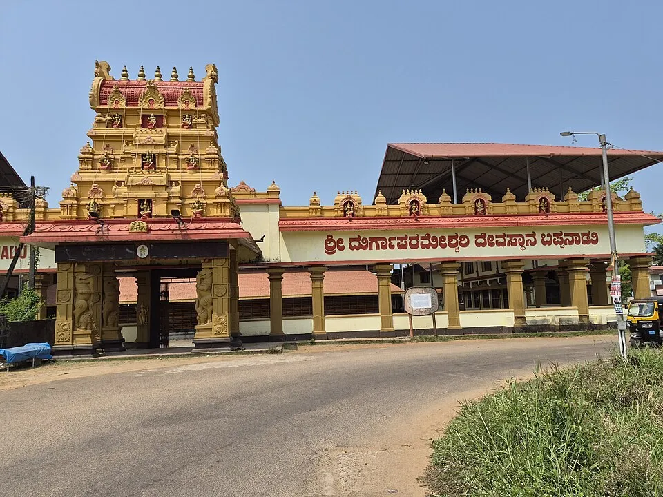 The gold and red gateway tower and long front of the Bappanadu Durgaparameshwari temple at Mulki, with its Kannada name board, under a blue sky