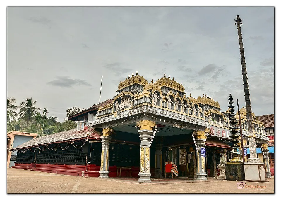 The decorated entrance of the Venkataramana temple at Karkala, with a tall lamp column beside it