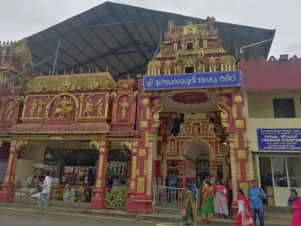 The red and gold gateway of the Durgaparameshwari temple at Kateel, with its Kannada name board and devotees at the door