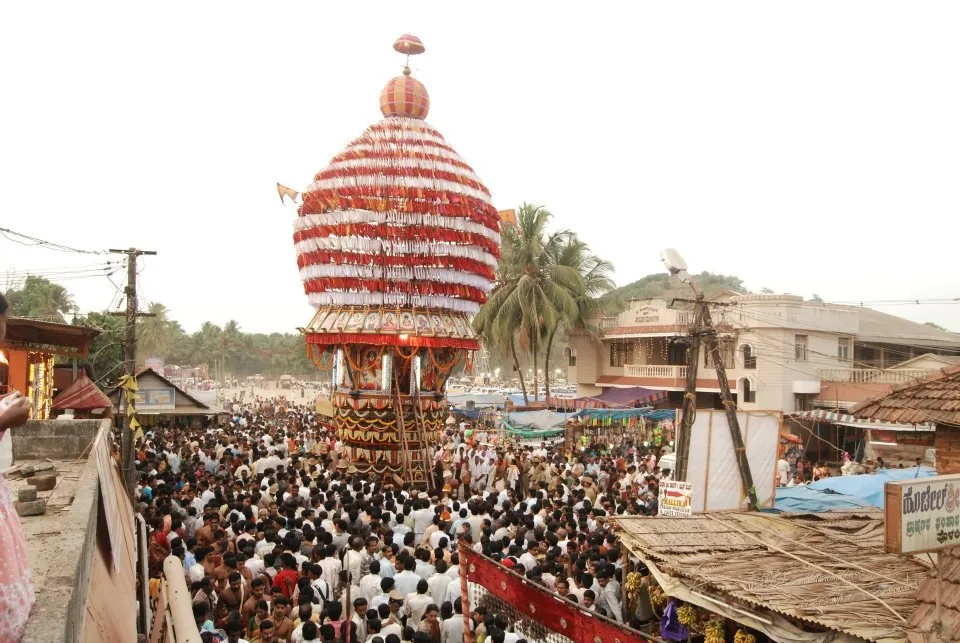 The festival car of the Polali temple, with a striped dome, rising above a very large crowd