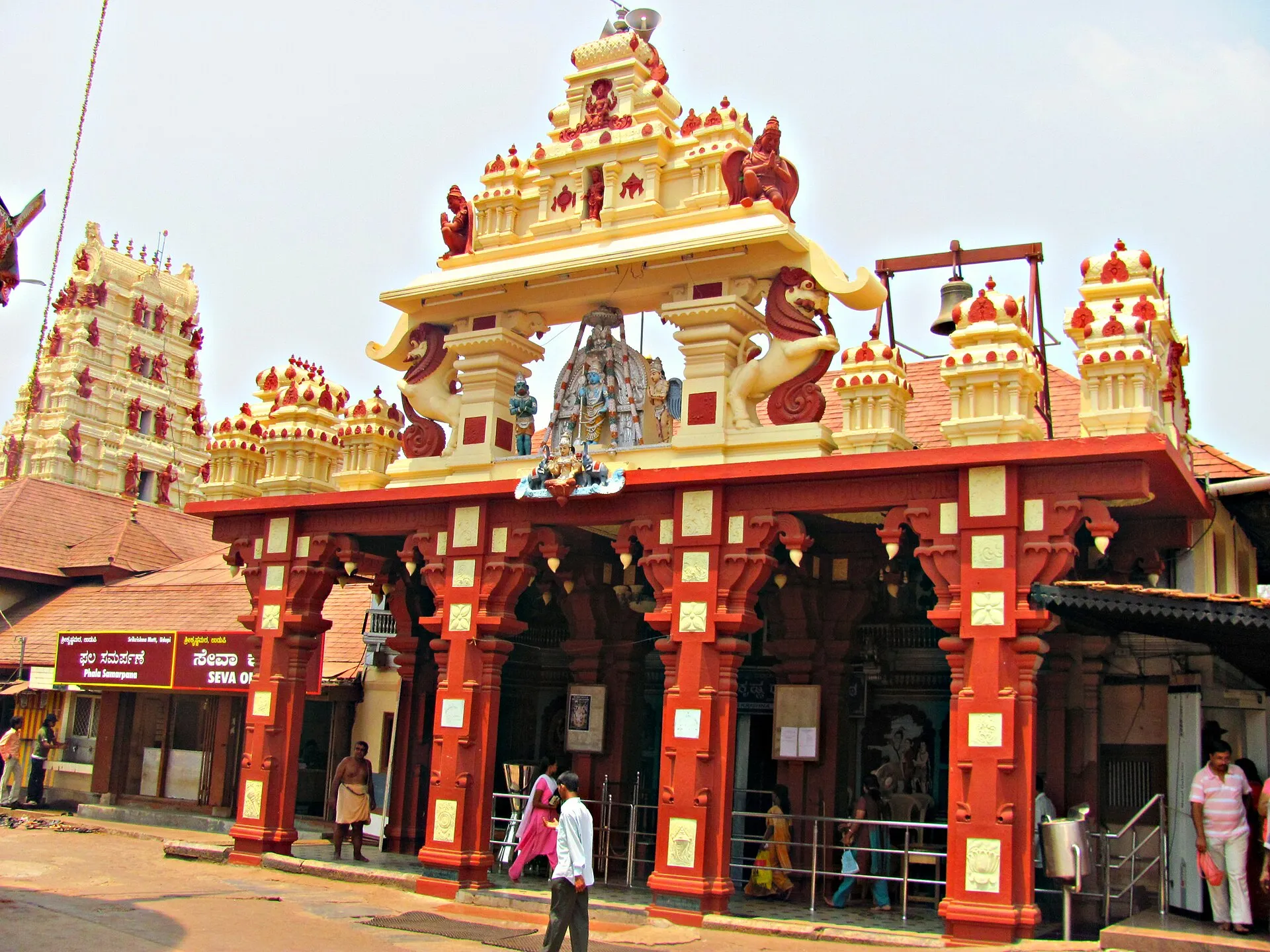 The ornate red and gold entrance of the Krishna temple at Udupi, with a white tower behind it